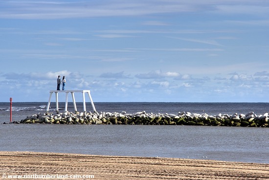 View from the beach to the breakwater and sculpture in the middle of the bay.